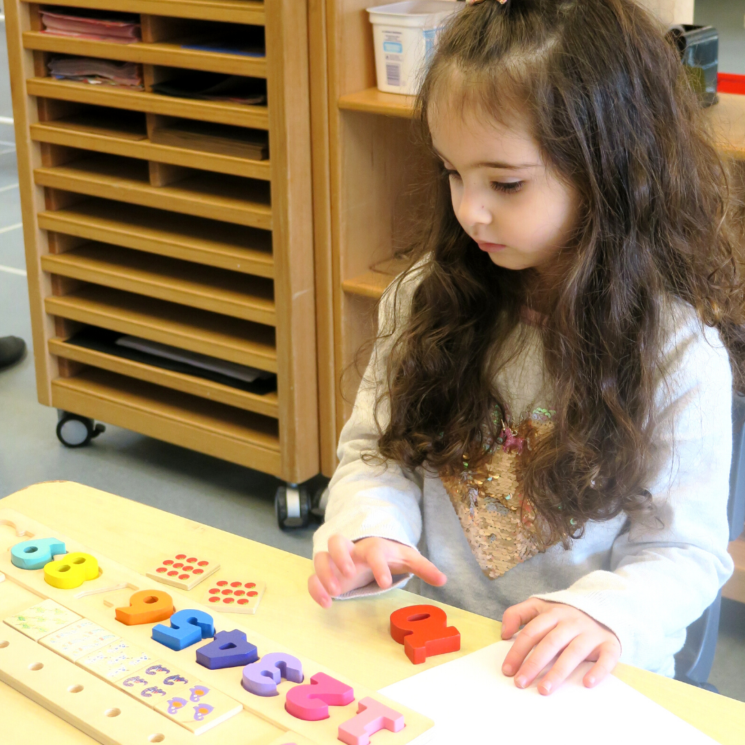 A child at a table playing with a number puzzle