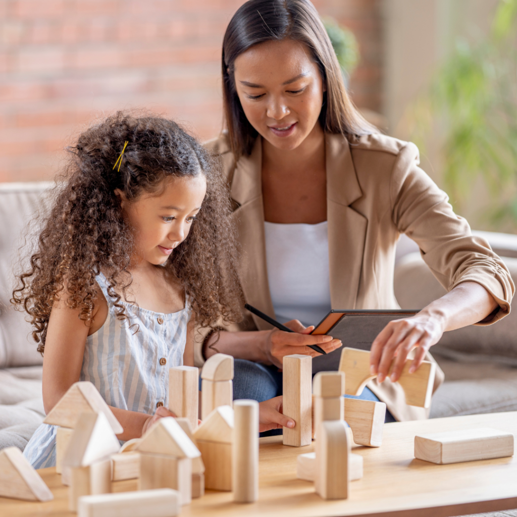 alt="Occupational therapist playing with a young girl with wooden blocks"